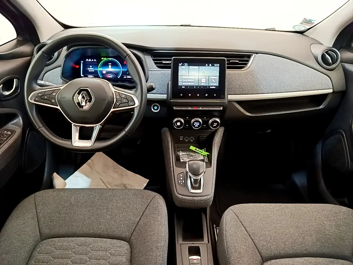 Vue intérieure avant de la Renault ZOE gris clair, avec tableau de bord numérique et écran tactile central.