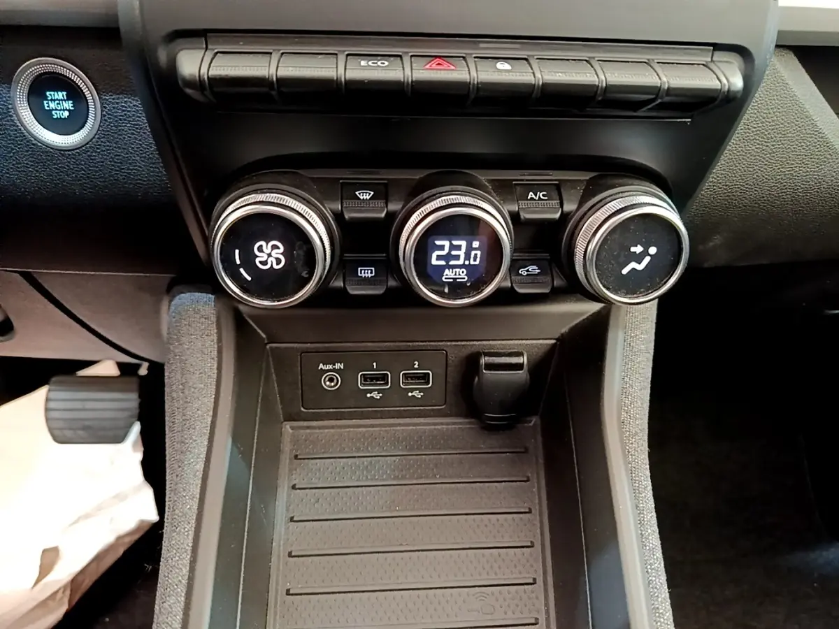 Vue rapprochée du tableau de bord central de la Renault ZOE gris clair, avec commandes climatisation et bouton démarrage visibles.