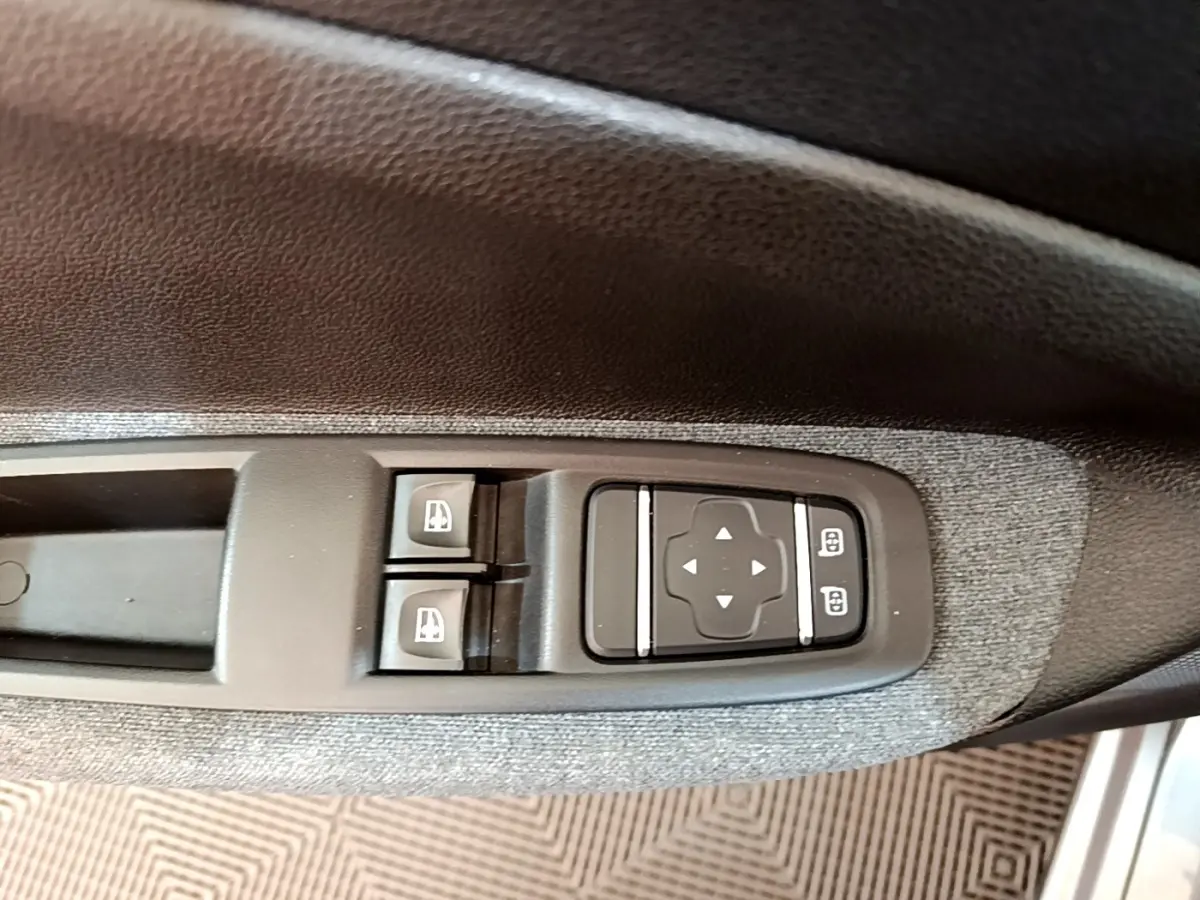 Détail des commandes de réglage des rétroviseurs et des vitres électriques sur la porte côté conducteur d’une Renault ZOE gris clair.