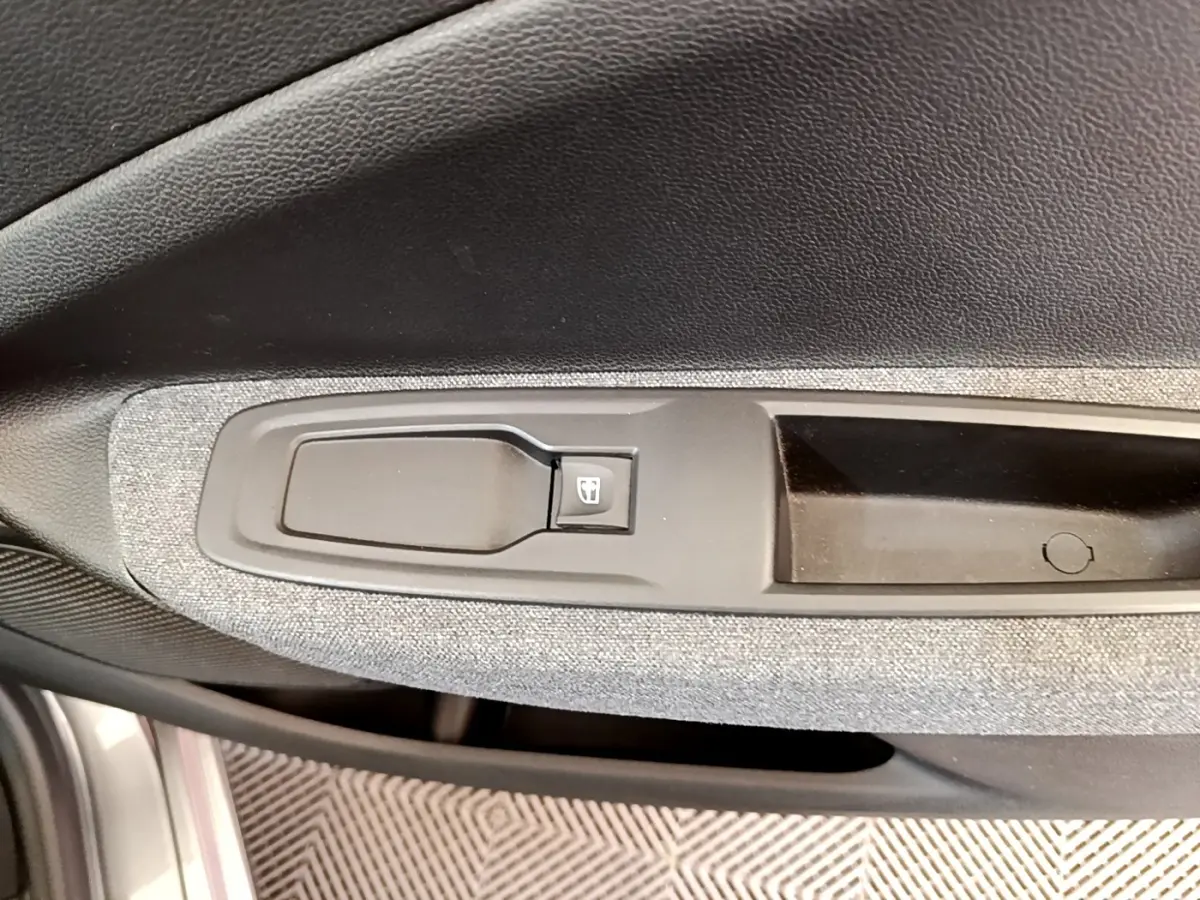 Détail de la commande de lève-vitre côté conducteur sur la porte intérieure grise d’une Renault ZOE électrique 2022.