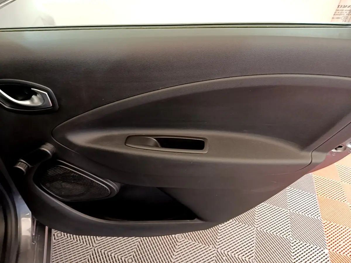 Vue rapprochée de la porte intérieure côté conducteur de la Renault ZOE gris clair, avec poignée et haut-parleur intégrés.