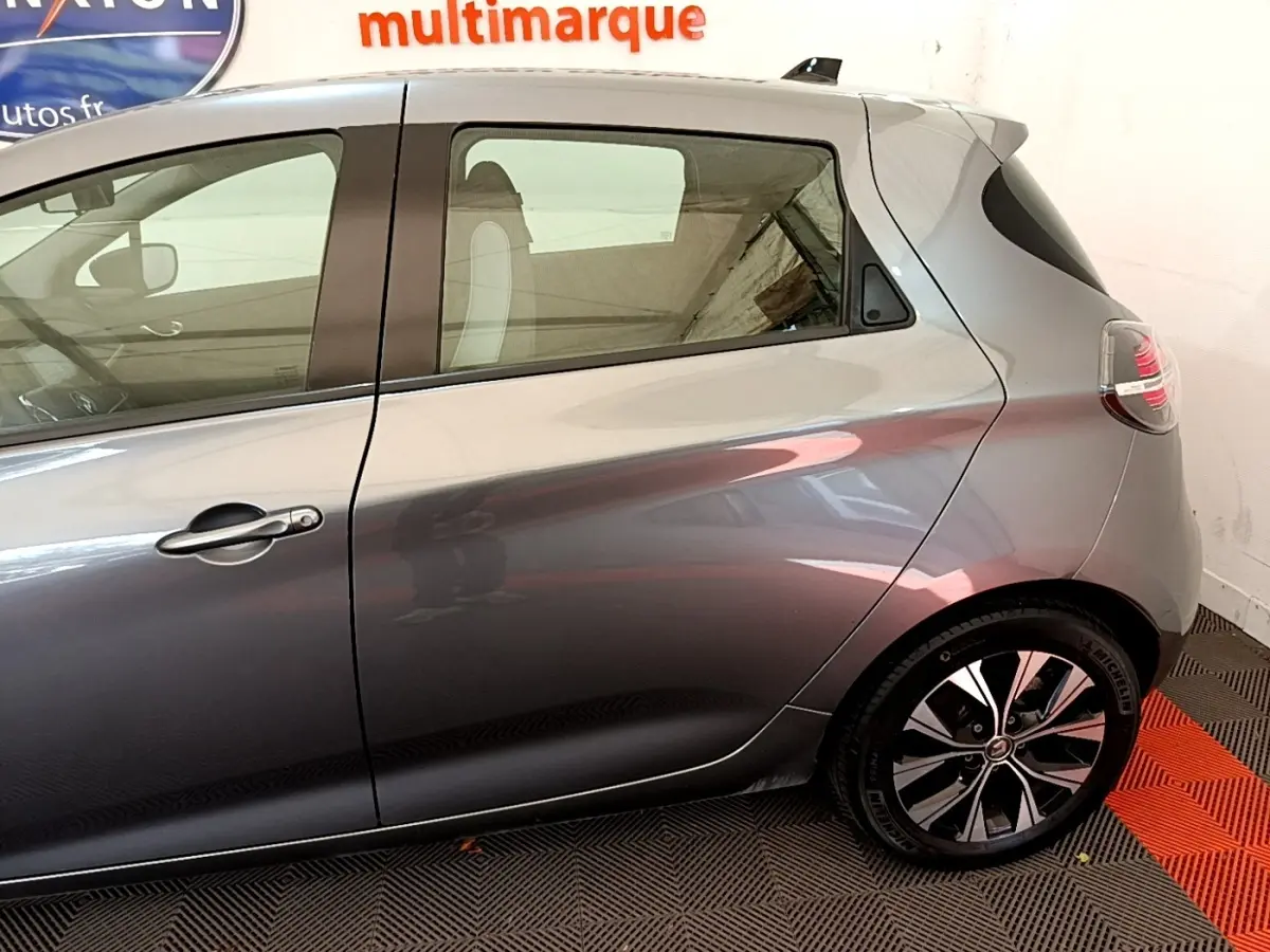 Profil droit de la Renault ZOE gris clair 2022 montrant la porte arrière et la jante au design moderne.