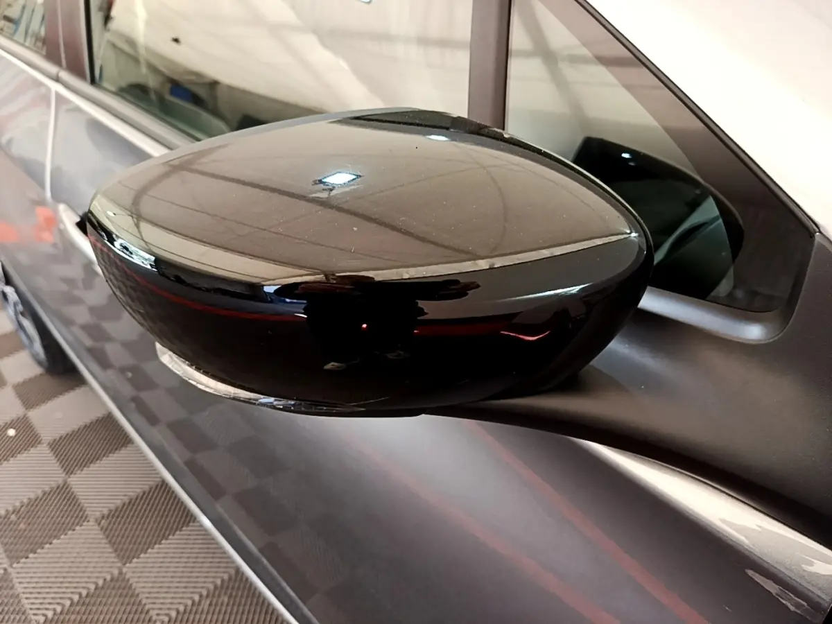 Rétroviseur noir en gros plan côté gauche sur Renault ZOE gris clair, finition électrique et moderne.
