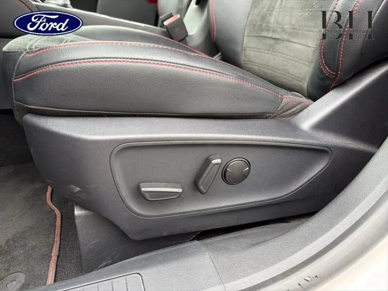 Gros plan sur le siège avant conducteur noir avec surpiqûres rouges et commandes électriques du Ford Kuga 2023.