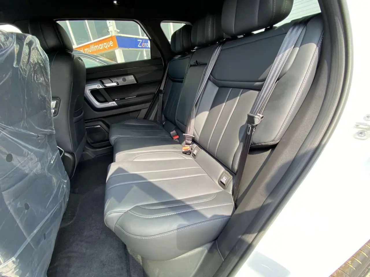 Vue intérieure côté droit des sièges arrière en cuir noir du SUV JAECOO J7 blanc khaki, version hybride 2026.