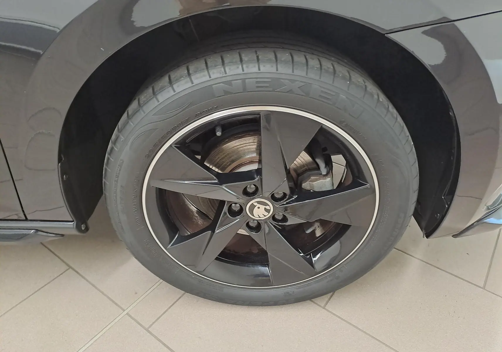 Gros plan sur la roue avant gauche noire nacrée d'une Skoda Scala Monte-Carlo avec jante étoile brillante.