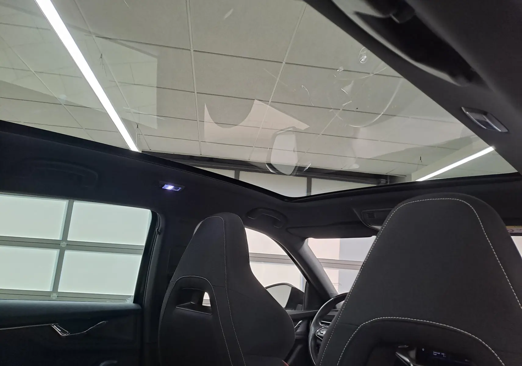 Intérieur du Skoda Scala 2022 noir Magic, vue arrière sur les sièges avant et toit panoramique vitré.