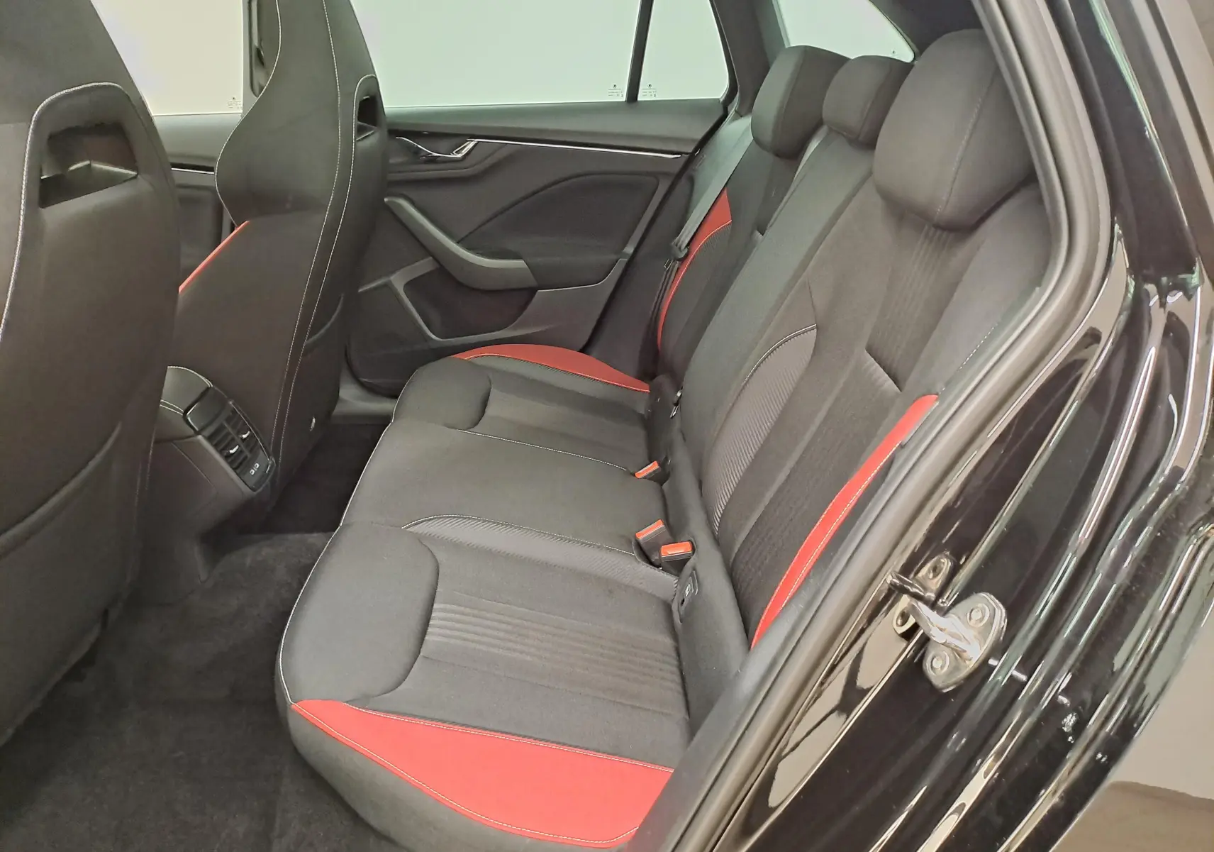 Vue côté droit de l'arrière d'une Skoda Scala 2022 noir Magic nacré avec sièges noirs et inserts rouges Monte-Carlo.