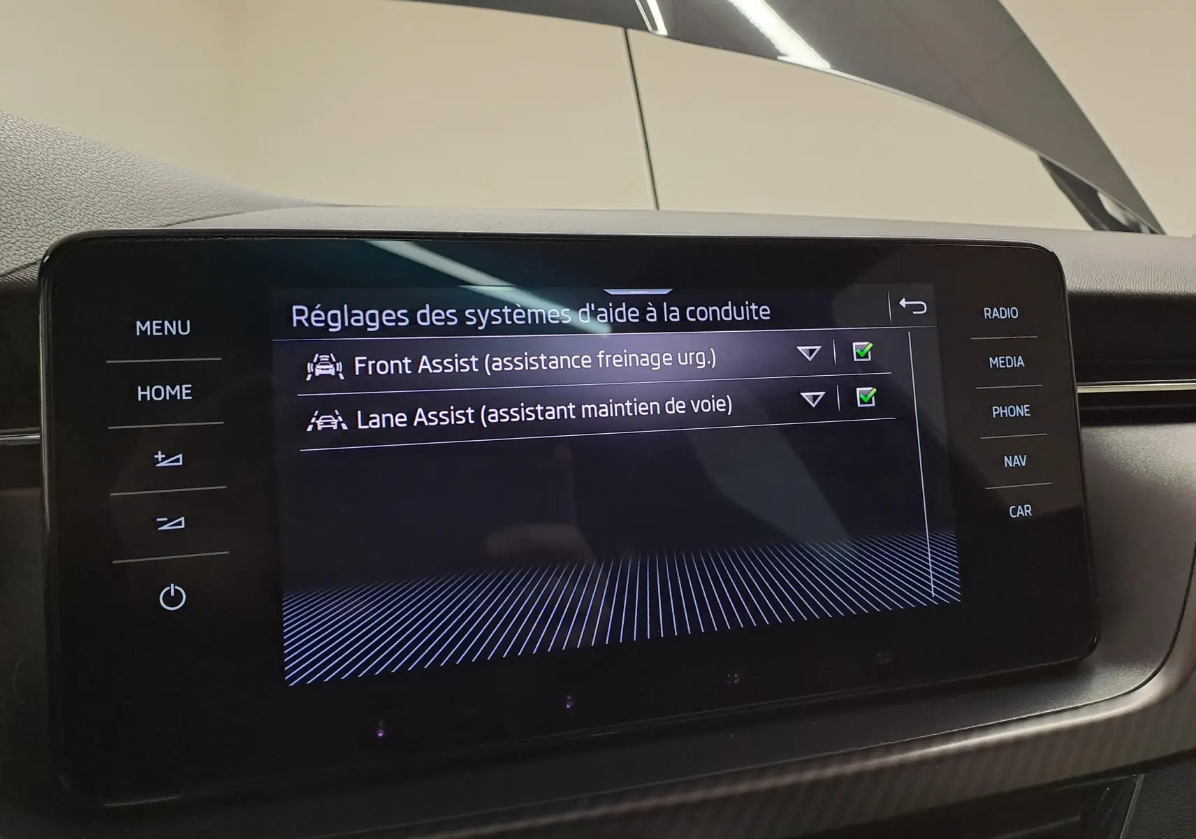 Écran tactile central du Skoda Scala 2022 montrant les réglages d'aide à la conduite activés, intérieur noir.