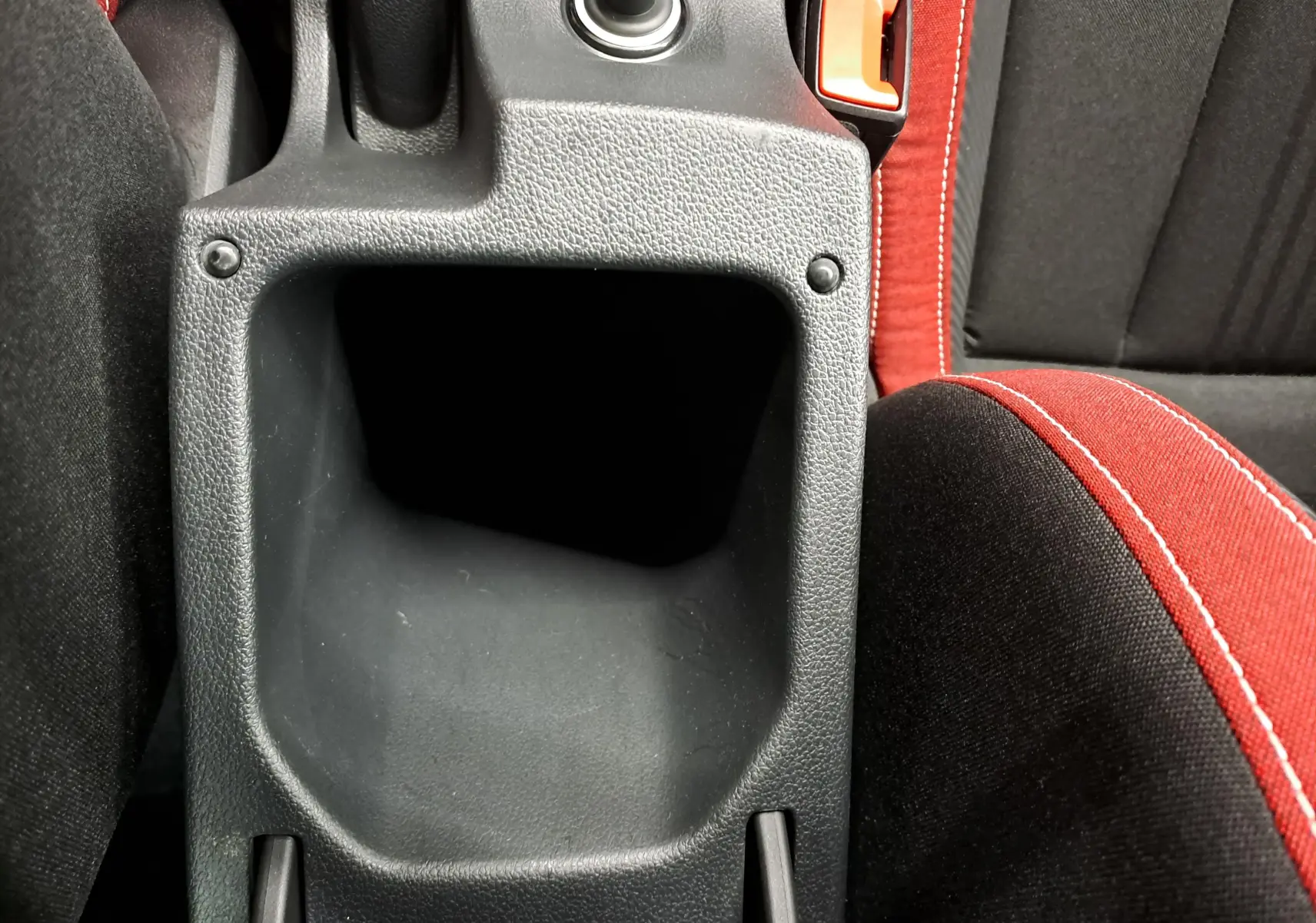 Gros plan sur le rangement central et la ceinture rouge avec surpiqûres blanches dans l’habitacle du Skoda Scala Noir Magic nacré.