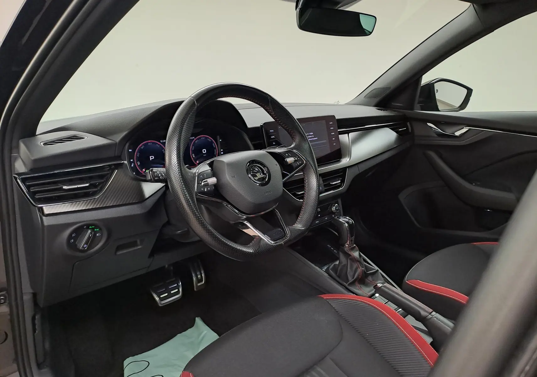 Intérieur du Skoda Scala 1.0 TSI Monte-Carlo 2022, vue côté conducteur, sièges noirs avec surpiqûres rouges et tableau de bord moderne.