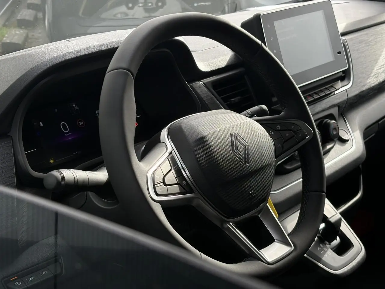 Vue rapprochée du volant et du tableau de bord numérique du Renault Trafic Fourgon blanc Glacier, avec écran tactile central.