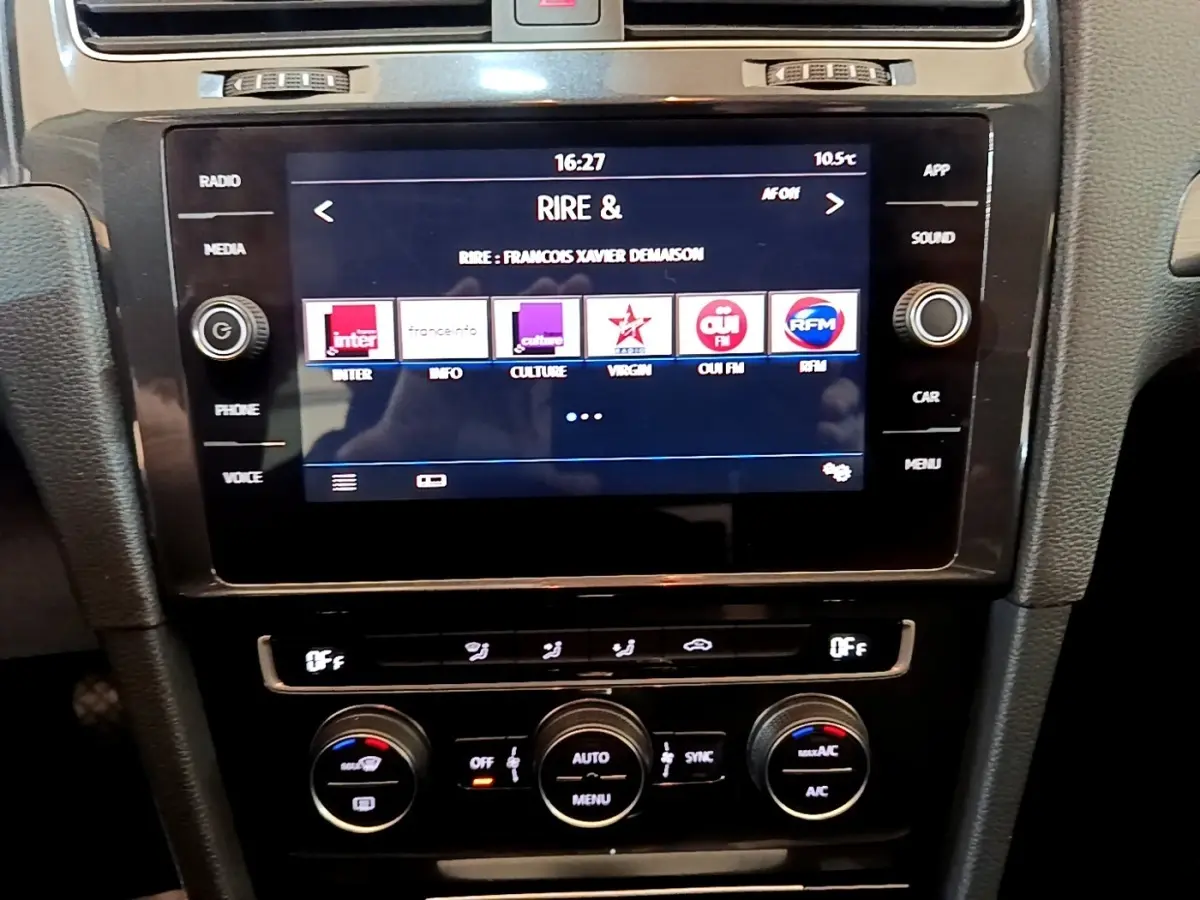 Vue rapprochée de la console centrale noire de la Volkswagen Golf 2019 avec écran tactile et commandes de climatisation.