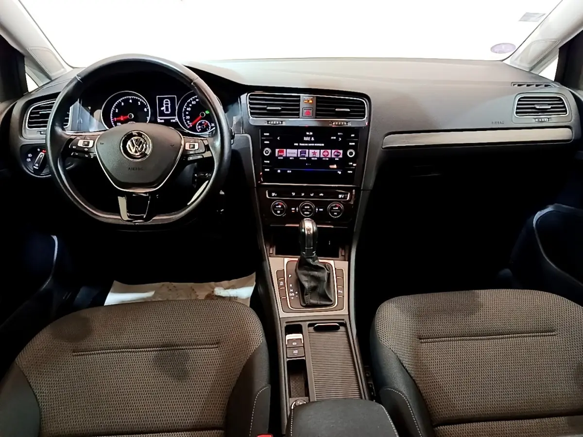 Vue intérieure avant de la Volkswagen Golf noire 2019, volant cuir multifonctions et console centrale avec écran tactile.