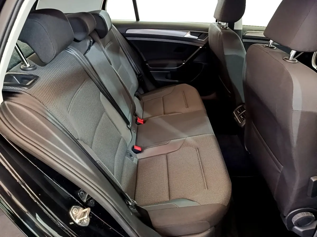 Vue intérieure côté gauche sur la banquette arrière grise d’une Volkswagen Golf noire, avec ceintures de sécurité visibles.