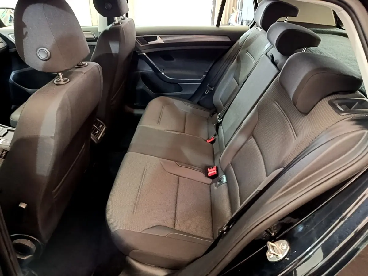 Vue intérieure côté droit sur la banquette arrière grise d’une Volkswagen Golf noire avec appuie-têtes et ceintures visibles.