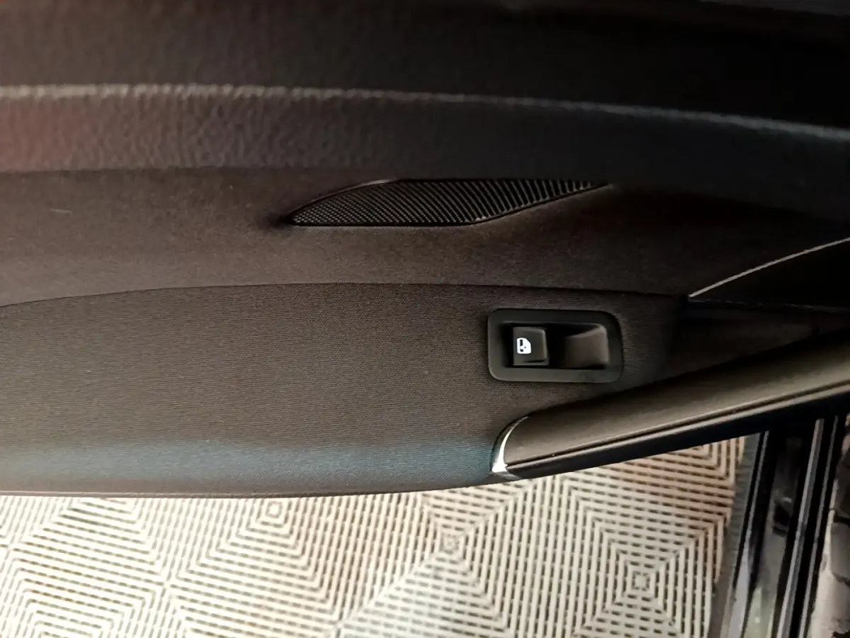 Vue rapprochée de la porte intérieure côté conducteur d’une Volkswagen Golf noire, bouton de verrouillage visible.