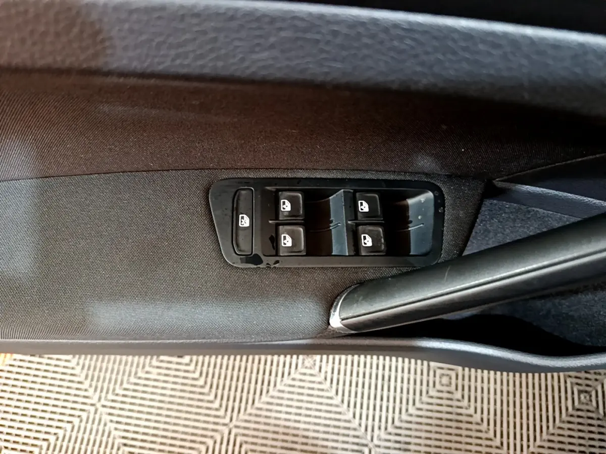 Gros plan sur les commandes des vitres électriques côté conducteur d’une Volkswagen Golf noire de 2019.