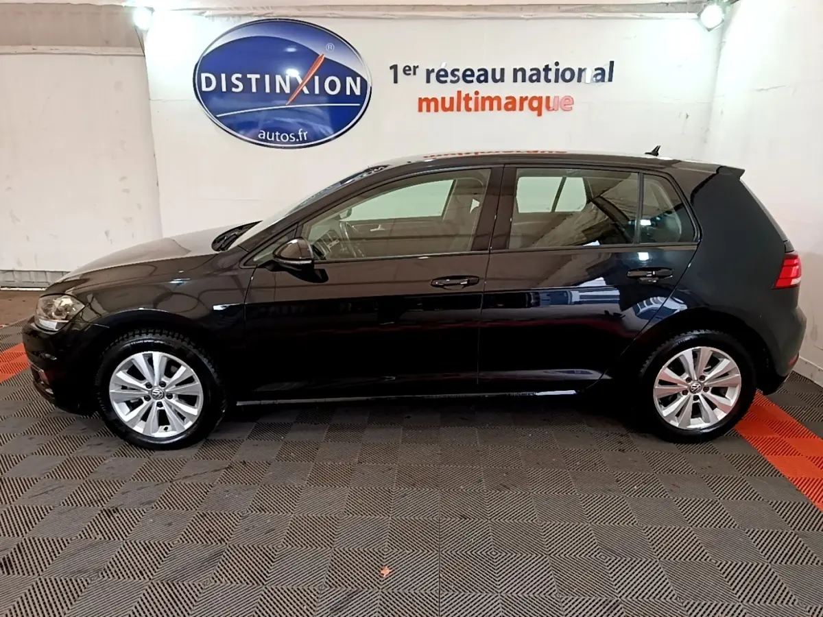 Profil côté gauche d'une Volkswagen Golf noire 2019 garée en intérieur avec jantes alliage et rétroviseurs électriques.