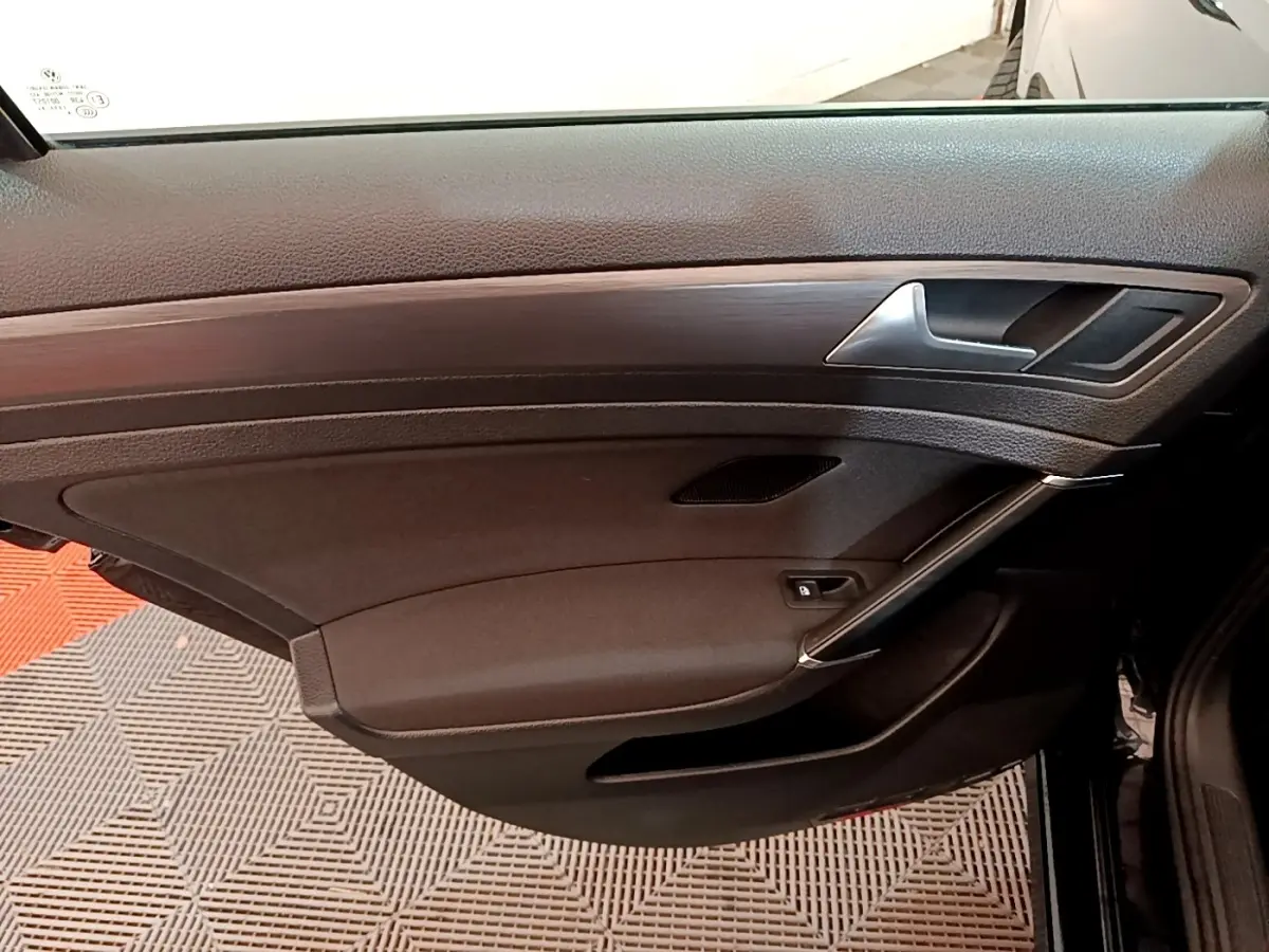 Vue intérieure de la porte avant droite noire de la Volkswagen Golf 2019 avec insert imitation bois et poignée argentée.