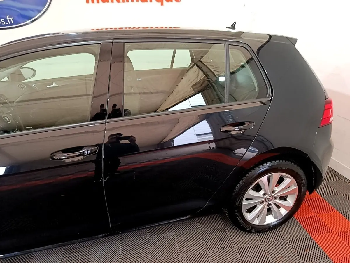 Vue latérale côté droit d'une Volkswagen Golf noire de 2019, mettant en valeur les jantes alliage et la carrosserie brillante.