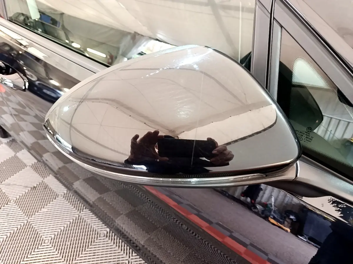 Rétroviseur droit noir brillant de Volkswagen Golf 2019, reflet net et carrosserie noire visible en arrière-plan.