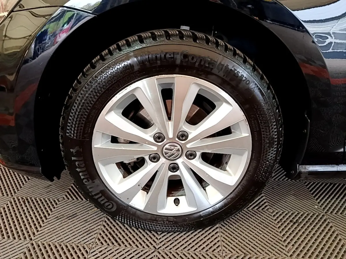 Gros plan sur la roue avant gauche d'une Volkswagen Golf noire, avec jante alliage et pneu hiver Continental.