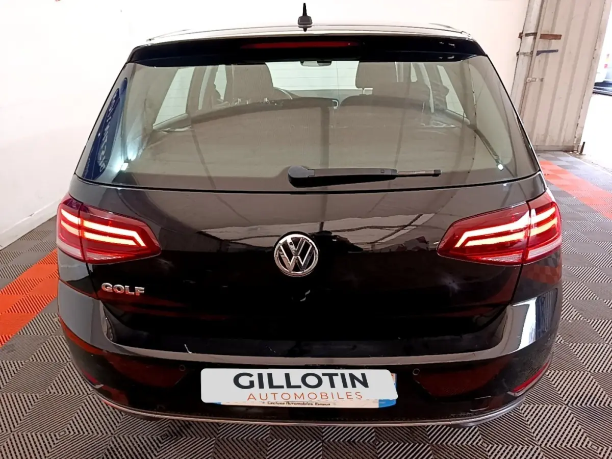 Vue arrière d'une Volkswagen Golf noire de 2019 avec feux LED allumés dans un garage.