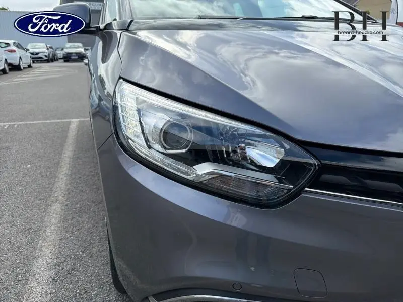Gros plan sur le phare avant droit gris Cassiopée du Renault Grand Scenic 2019, avec reflets du ciel nuageux.