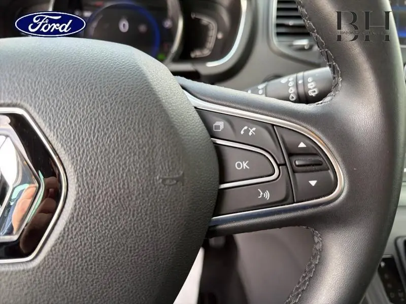 Gros plan sur le volant cuir côté droit du Renault Grand Scenic gris Cassiopée, avec commandes multifonctions visibles.