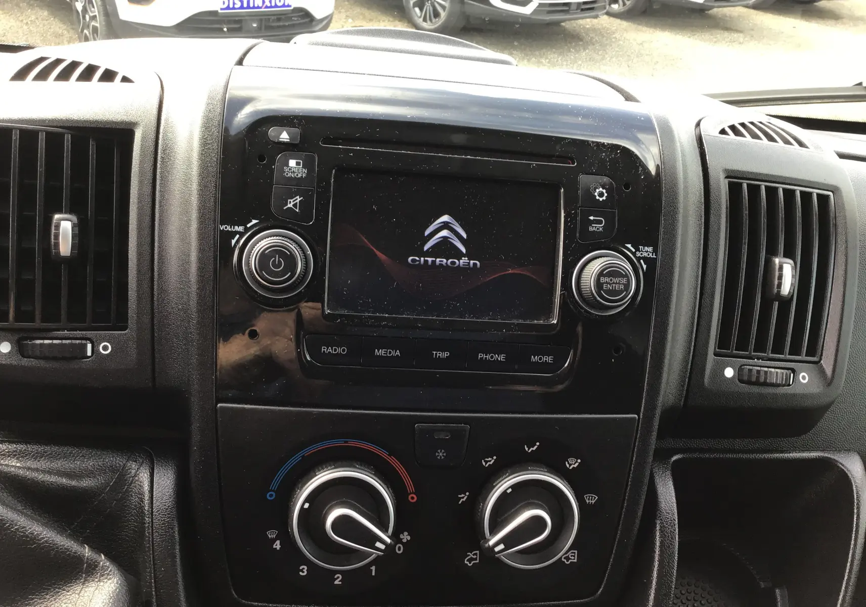 Tableau de bord noir du Citroën Jumper gris, avec écran central affichant le logo Citroën et commandes climatisation visibles.