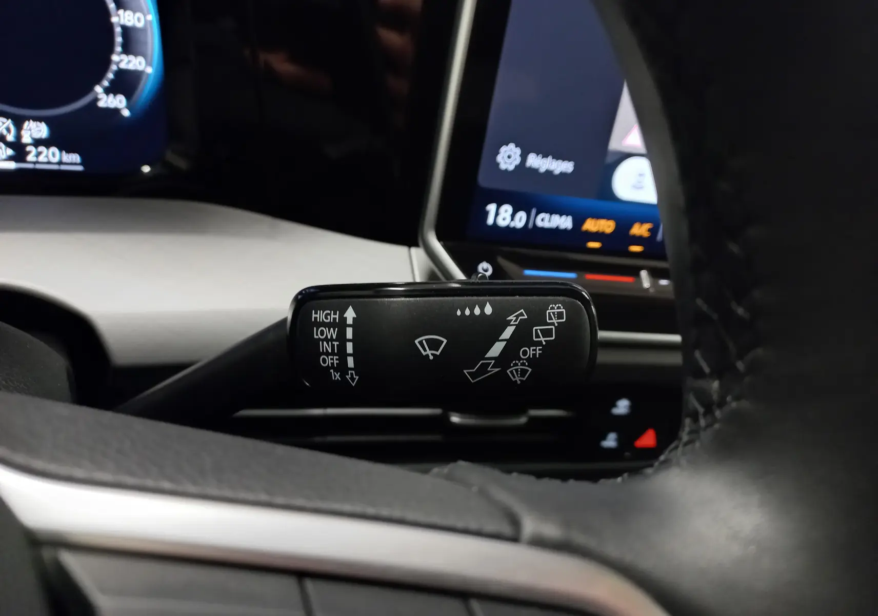 Gros plan sur la manette d’essuie-glace à gauche du volant d’une Volkswagen Golf Bleu Anemone, tableau de bord en arrière-plan.