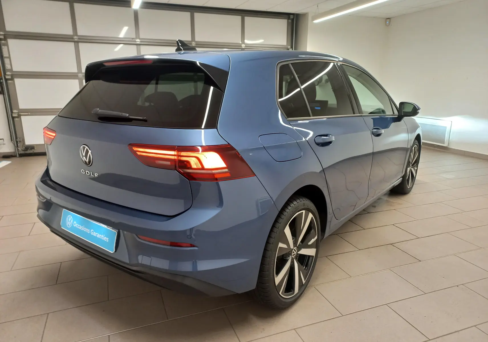 Vue 3/4 arrière droite d'une Volkswagen Golf 1.5 TSI bleu Anemone avec jantes alliage léger 18 pouces Catania.