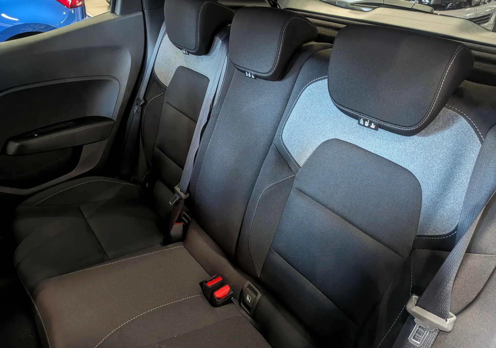 Vue intérieure arrière de la banquette tissu noir et gris de la Renault Clio V 2025 avec ceintures de sécurité visibles.
