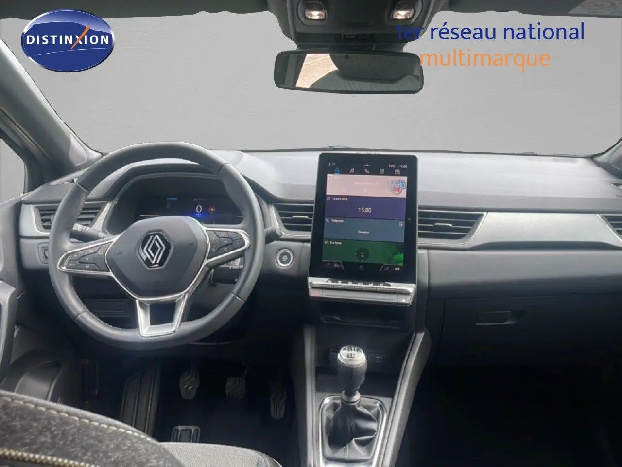 Vue intérieure avant du Renault Captur 2025, tableau de bord gris avec écran tactile vertical et levier de vitesse manuel.