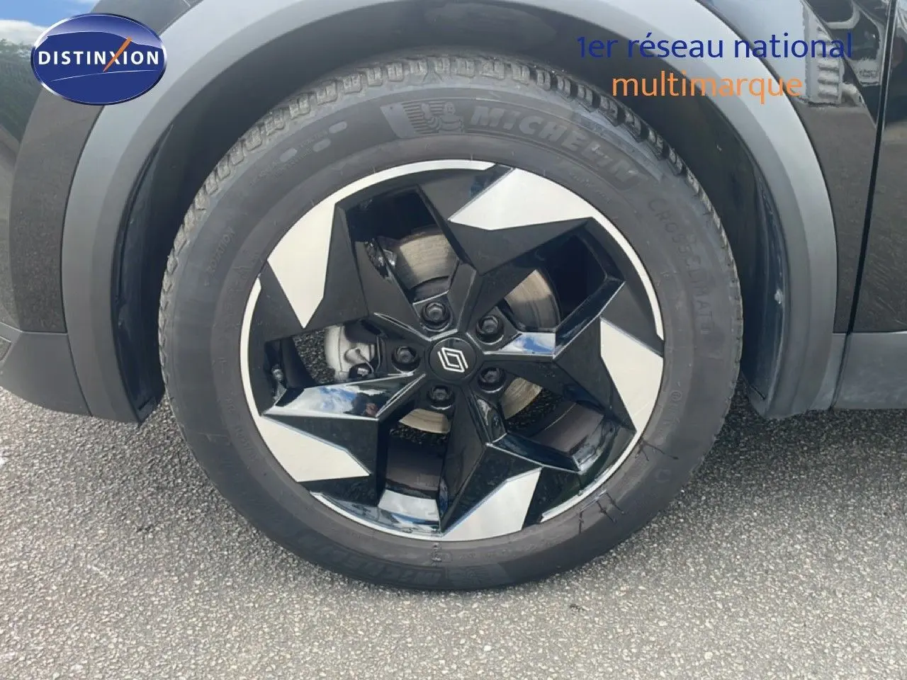 Gros plan sur la roue avant droite du Renault Captur noir étoile métal avec jante noire et argentée au design géométrique.