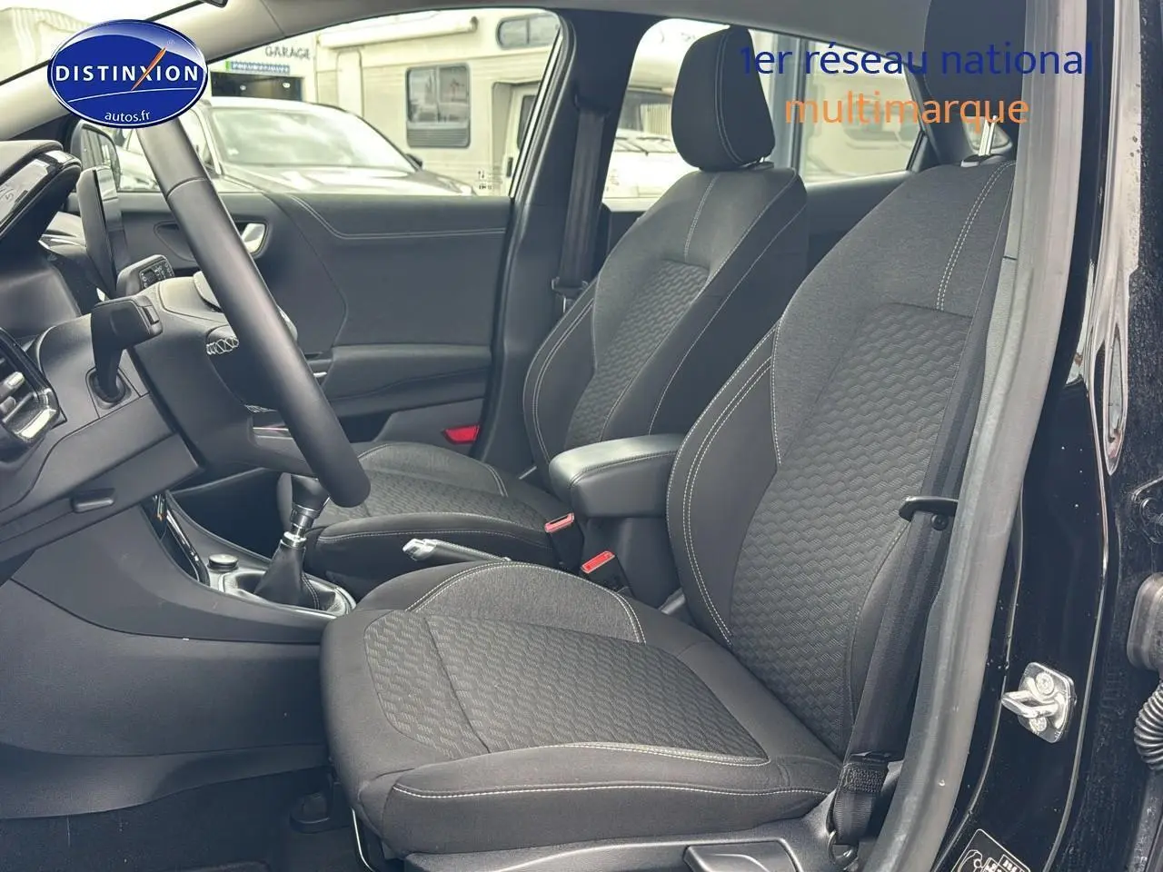 Intérieur avant du Ford Puma noir 2023, vue côté conducteur montrant sièges tissu noirs et console centrale avec boîte manuelle.