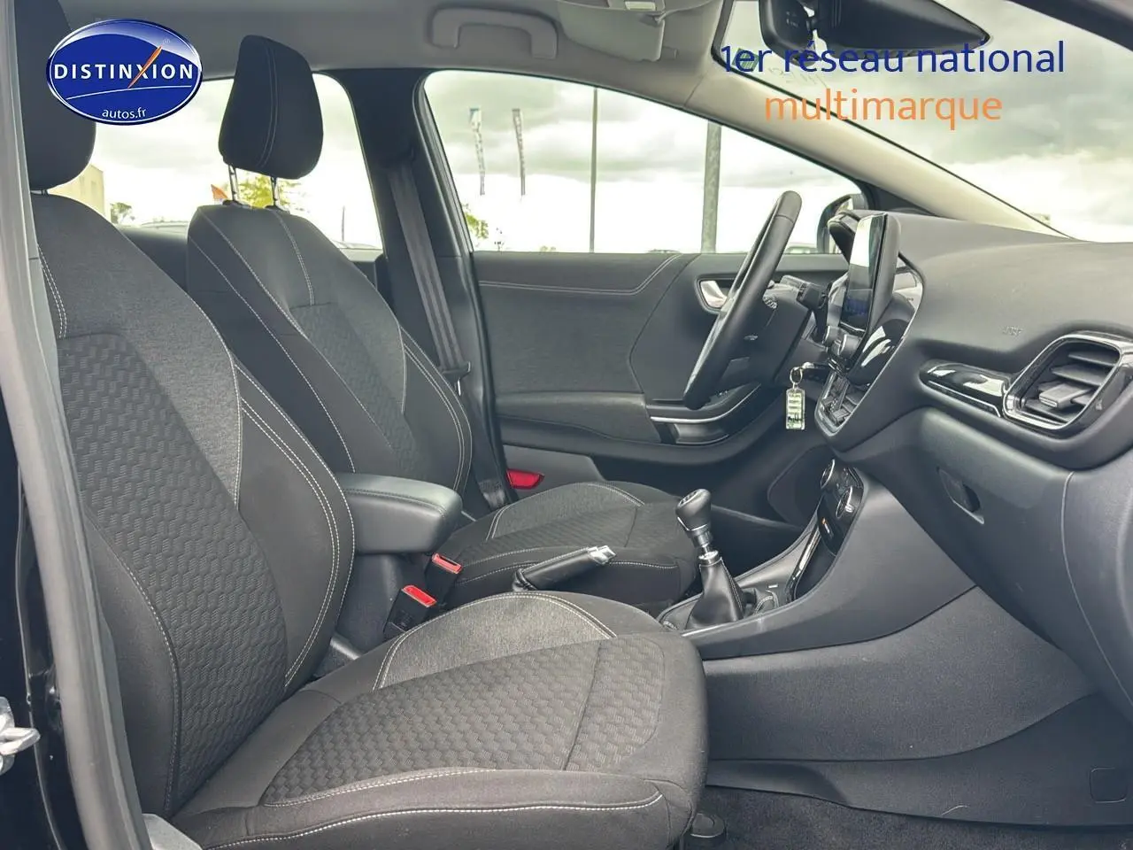 Intérieur avant du Ford Puma 2023 noir, vue côté gauche montrant sièges tissu noirs et console centrale avec boîte manuelle.