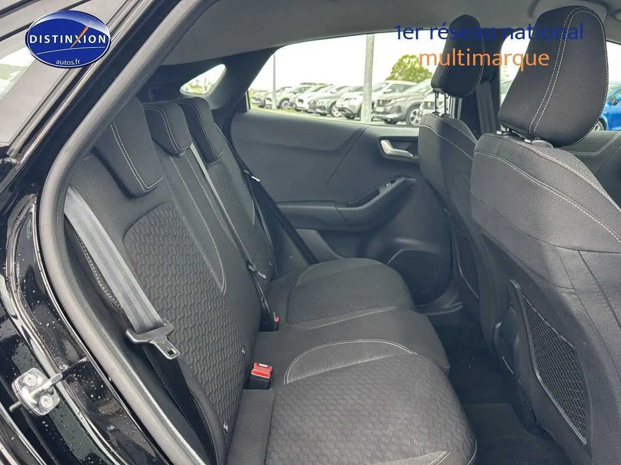 Vue côté gauche de l'habitacle arrière du Ford Puma noir 2023, montrant les sièges en tissu avec surpiqûres blanches.