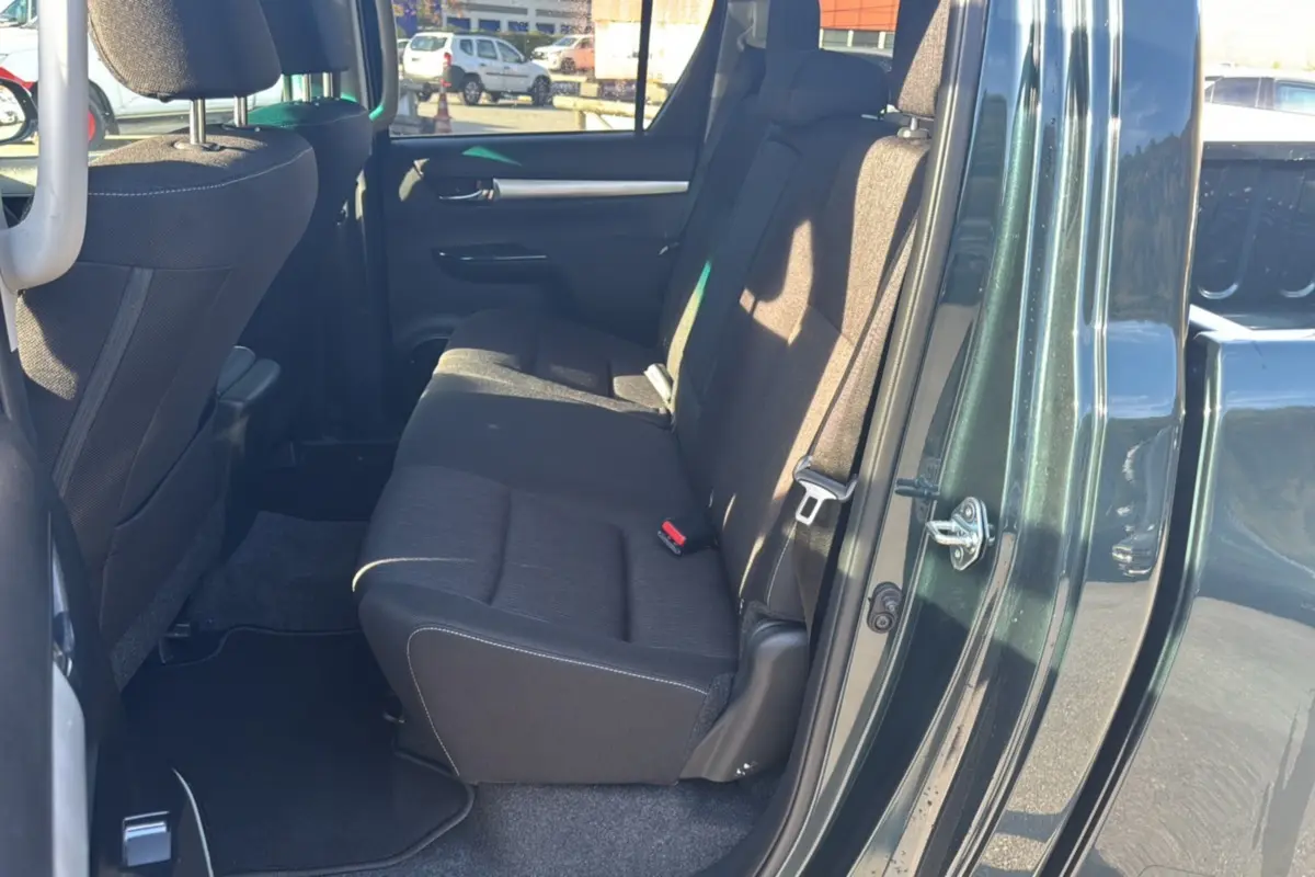 Vue côté droit arrière du Toyota Hilux 4x4 2025 vert métal, montrant la banquette arrière en tissu noir.