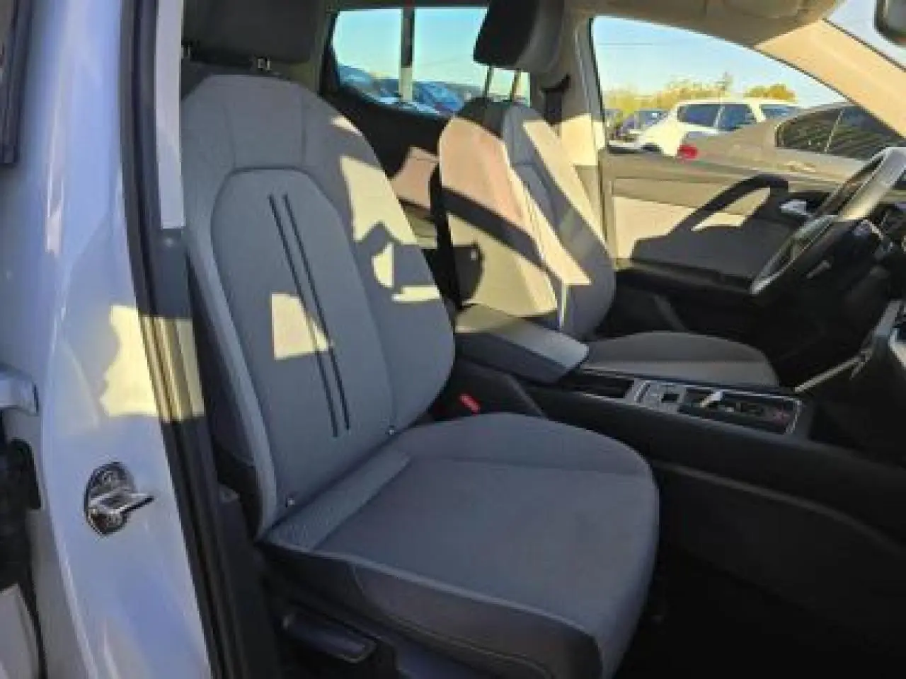 Vue intérieure côté conducteur de la SEAT LEON blanche 2024, sièges tissu gris et console centrale moderne.