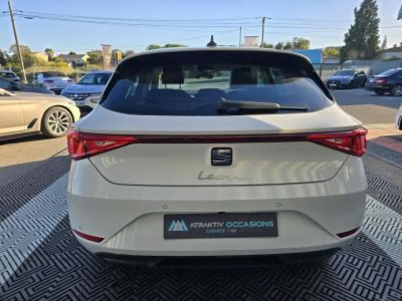 Vue arrière d'une SEAT Leon blanche 2024 avec feux arrière reliés par une bande lumineuse rouge.