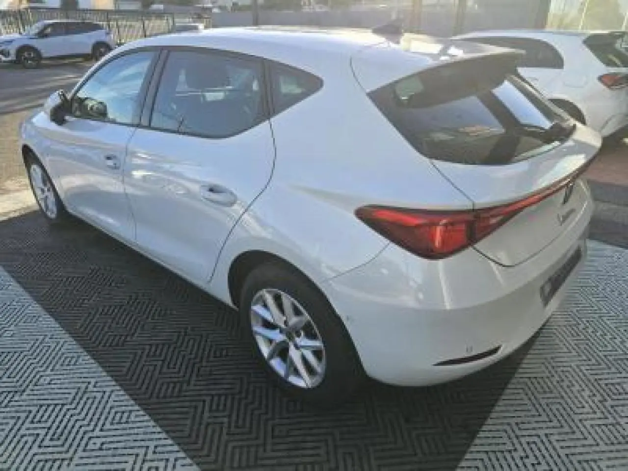 Vue 3/4 arrière droite d'une SEAT Leon blanche 2024 avec jantes alliage et vitres teintées.