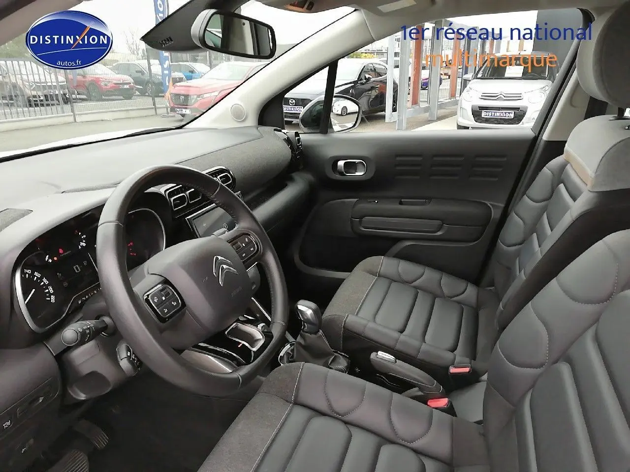 Intérieur du Citroën C3 Aircross blanc polar, vue côté conducteur montrant le tableau de bord et les sièges noirs en cuir.