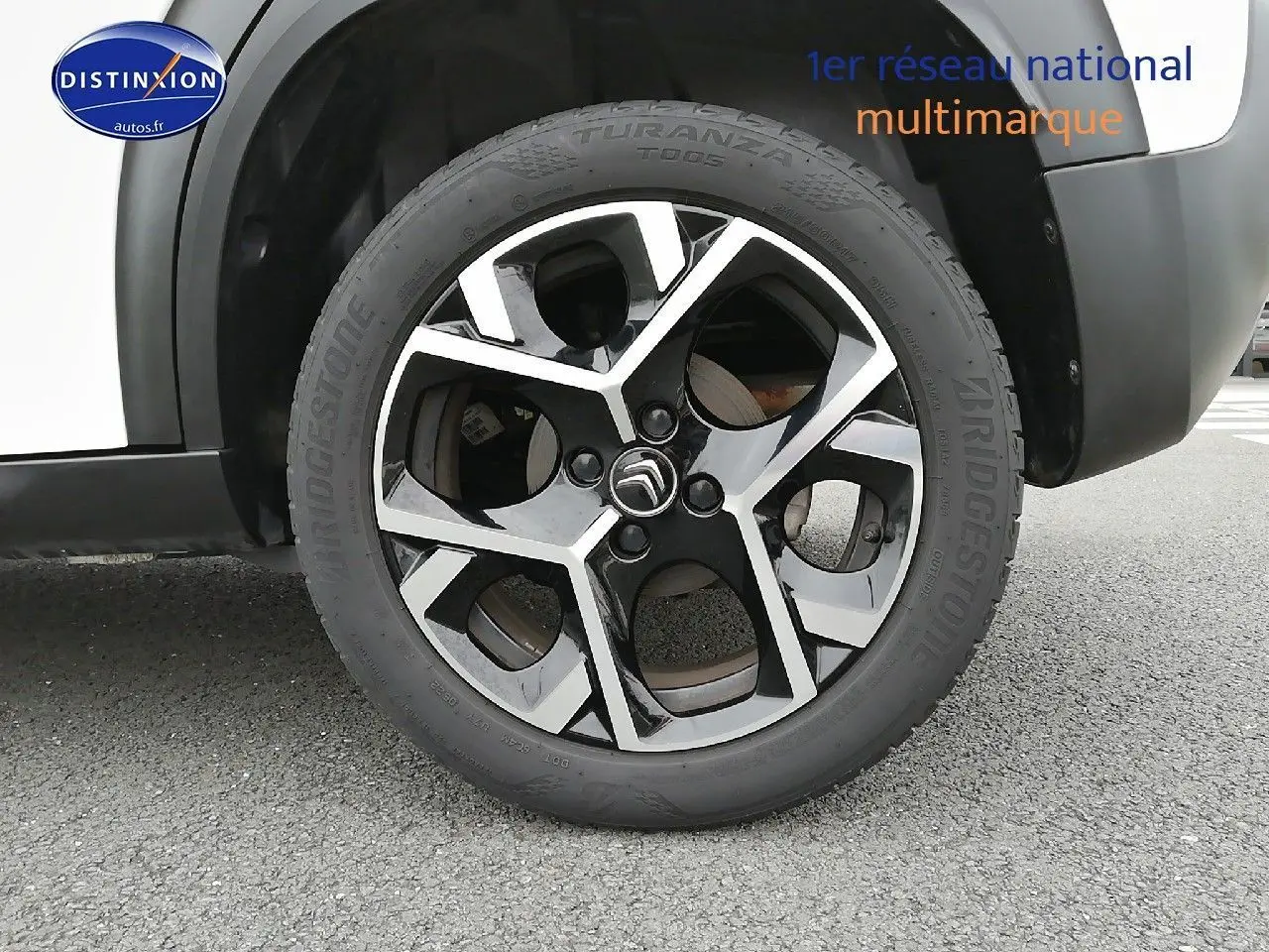 Gros plan sur la roue avant droite d'une Citroën C3 Aircross blanc polar, avec jante alliage noire et argentée.