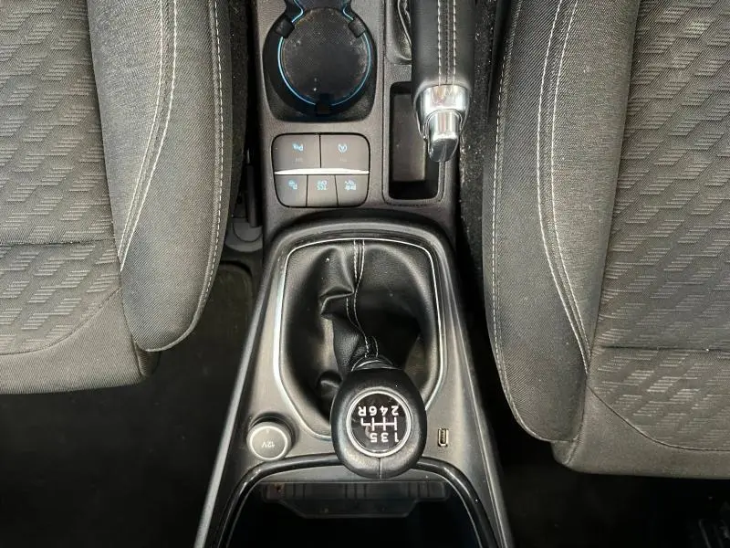 Vue plongeante sur le levier de vitesses manuel noir et les sièges tissu gris du Ford Puma blanc Glacier 2022.