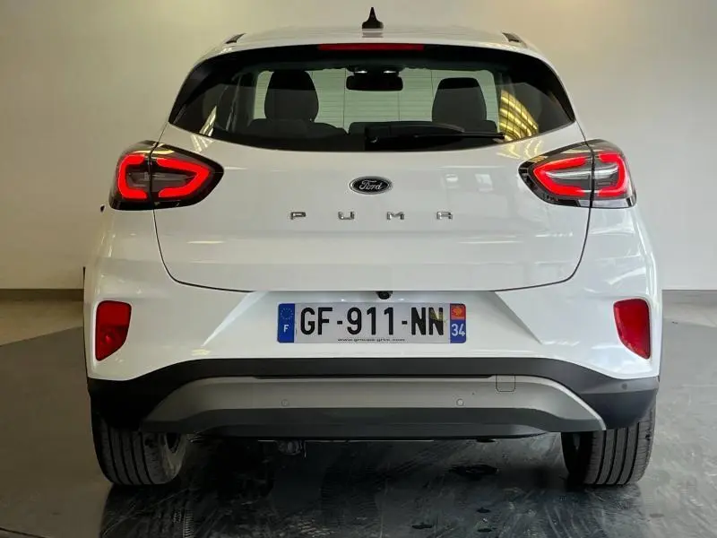Vue arrière d'une Ford Puma blanc glacier avec feux arrière LED allumés et hayon électrique visible en intérieur neutre.