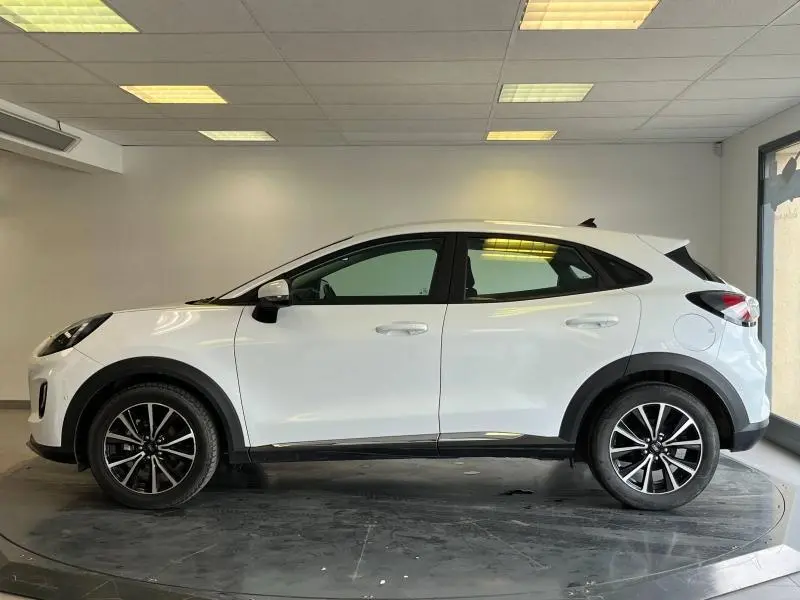 Profil côté gauche du Ford Puma blanc Glacier 2022 avec jantes alliage et protections noires sous éclairage intérieur