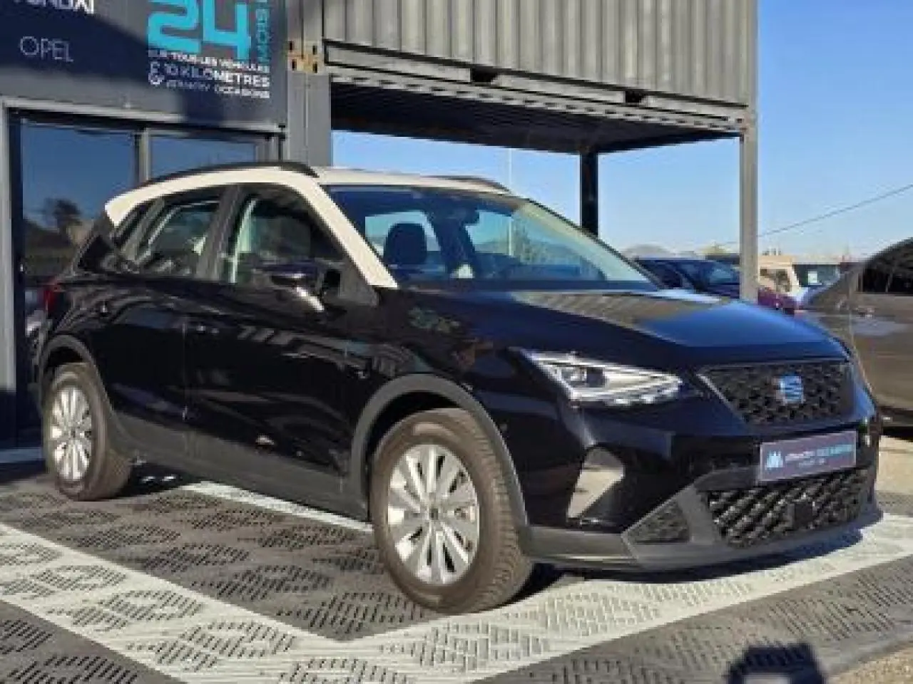 SEAT Arona 2024 noir minuit avec toit blanc, vue 3/4 avant mettant en valeur ses jantes alliage et calandre distinctive.
