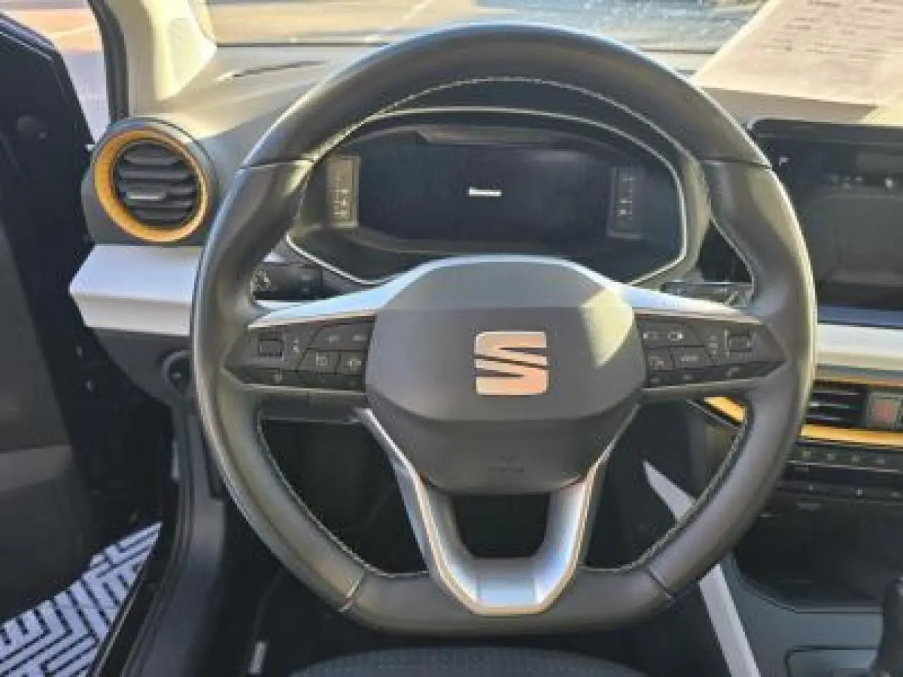 Volant sport cuir multifonction au méplat du SEAT Arona 2024 vu de face, avec tableau de bord digital en arrière-plan.